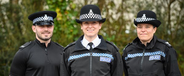 Three police officers in uniform smiling for the camera