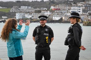 Two uniformed police officers talking to a woman in a blue jacket